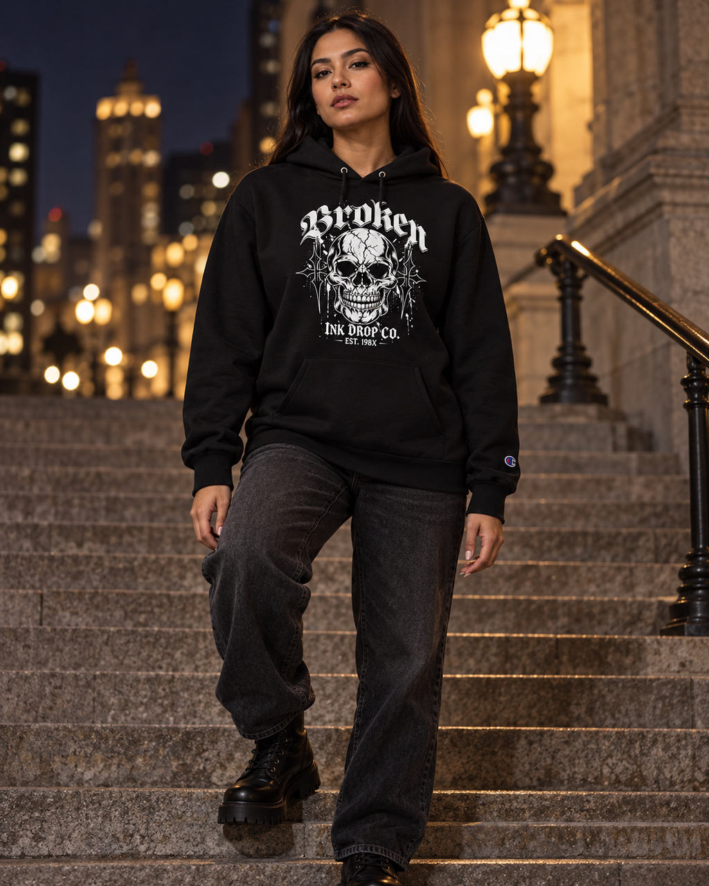 Black unisex hoodie worn outdoors, front skull graphic and drawstring hood